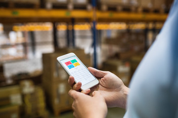 Man warehouse worker with a smartphone.