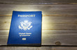 A US passport laying on a wood table with a spotlight on the center of the passport.