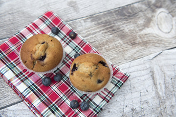 Two blueberry muffins on a wooden background 