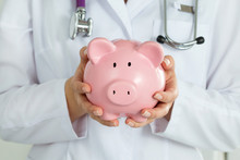 Female Doctor Holding Piggy Bank