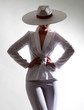 Beautiful young girl with a beautiful figure in a white trouser suit and a wide-brimmed white hat posing against a white background in the studio.