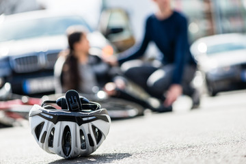 Close-up of a bicycling helmet fallen down on the ground after accidental collision between bicycle and a 4x4 car