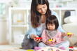 © spass - Pretty japanese woman playing with her cute laughing baby girl on the floor