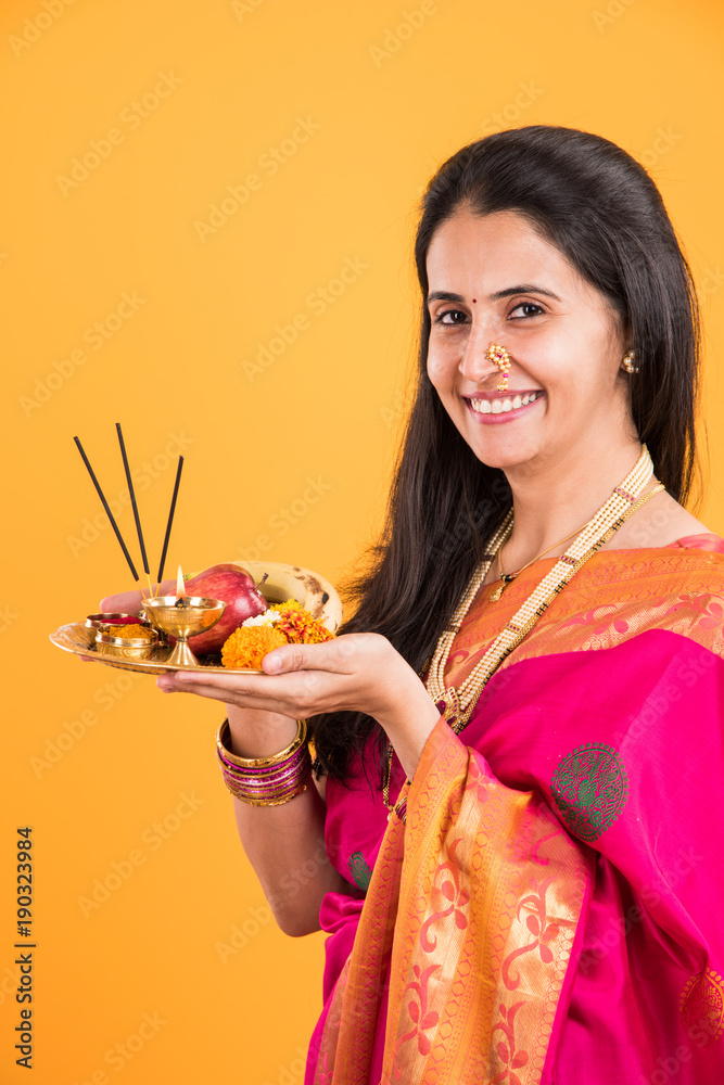 pujaranidaliyvlog Indian woman performing puja, indian girl with pooja thali or puja thali,  portrait of a beautiful young lady with pooja thali, isolated over yellow  background 스톡 사진 | Adobe Stock