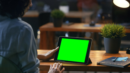 Aufkleber - Young Woman Sits at Her Wooden Desk Uses Tablet Computer with Mock-up Green Screen, She Uses Various Swipe and Touch Gestures.