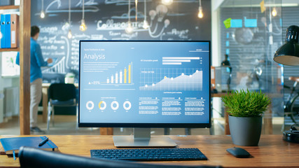 Poster - Personal Computer with Mobile Application Design Showing on the Monitor Stands on the Office Desk, In the Background Man Working in the Daytime Office Environment.