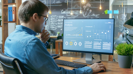 Poster - Financier Works on a Personal Computer Showing Statistics, Graphs and Charts. In the Background His Coworker and Creative Office.