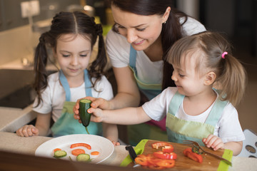 Happy family in the kitchen. Mom and daughters playing and having fun in the kitchen preparing.