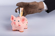 © Christian Schulz - Hand mit Handschuh greift nach Ersparnissen, Sparschwein