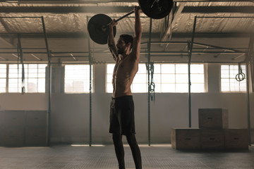 Wall Mural - Muscular man exercising with barbell