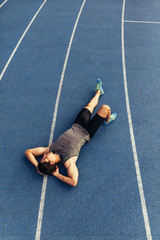 Wall Mural - sprinter relaxing by lying on the running track