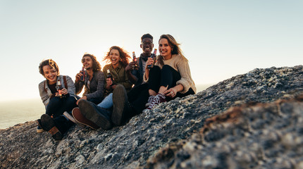 Wall Mural - Diverse group of friends having beers on mountain top