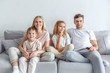 © LIGHTFIELD STUDIOS - interested young family watching movie on couch at home