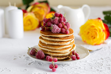 Wall Mural - Stack of pancakes with raspberry, red currant, cream and honey on white table cloth