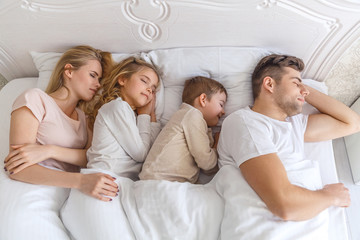 top view of young family sleeping together in bed