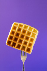 Wall Mural - Belgian waffle with honey decorated sweet cherry pinned on a fork on violet background