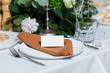 © bearmoney - Wedding table setting with blank guest card, napkin, succulent and dish on a wooden plate. Rustic decor in brown tones