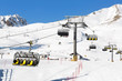 Skiers going up on the chairlift against bright blue sky- ski resort in Italy on sunny winter day