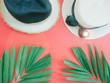 flat lay for summer concept with beach hat on red background and green tropical palm leaf