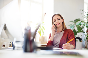 Wall Mural - Businesswoman in wheelchair at the desk in her office.