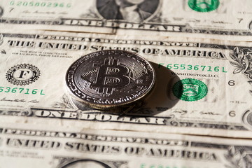 Wall Mural - silver bitcoin coin lying on united states dollars, cryptocurrency concept