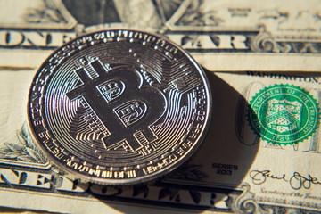 Wall Mural - silver bitcoin coin lying on united states dollars, cryptocurrency concept