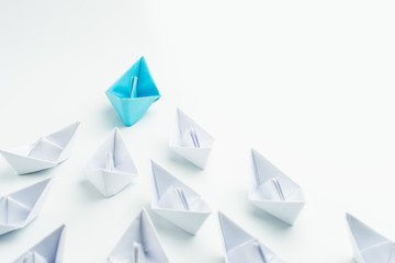 Wall Mural - Leadership concept with blue paper ship leading among white on white background.