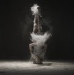 Young dancer doing a headstand in dust cloud view