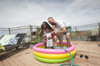 © Jasper Cole/Blend Images - Parents posing for selfie with children in inflatable swimming pool