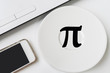 Happy Pi Day, written in black pen on white. On the table there is a laptop, a plate, a phone.