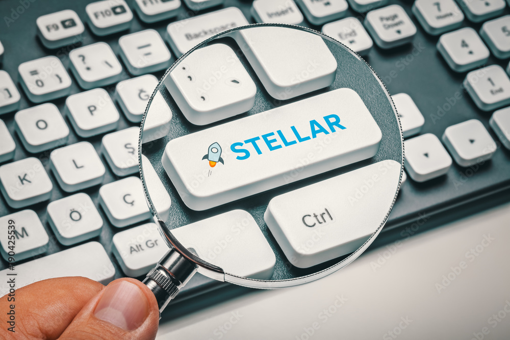 magnifying glass in hand focused on computer key with stellar lumens logo. cryptocurrency trading concept