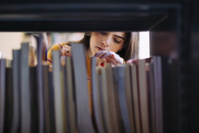Woman Searching Books On Shelf At Library