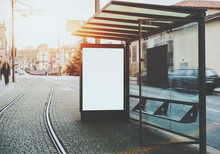 Glass And Metal Tram Stop With Railway Track Near And Blank White Mock-up Of Informational Banner Inside; Empty Advertising Billboard Placeholder Stand In Urban Settings Next To Tramway And City Road