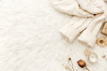 Warm sweater and dried flowers at white background. Cozy vintage. Flat lay, top view