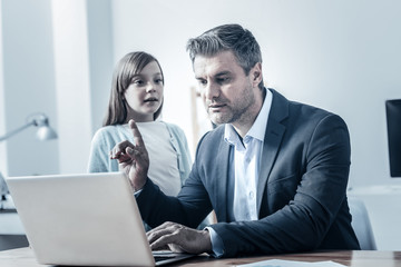 Several minutes honey. Adult businessman working hard on a laptop and asking his loving to wait a second while both spending time together.