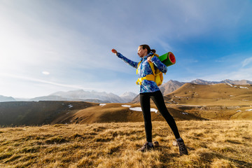 active young girl in a blue jacket travels through the Caucasus mountains with a backpack