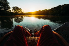Young Man Sits In Armchair By The Lake And Meets Sunrise Or Sunset, Point Of View. Recration Relaxation Concept