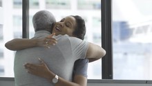 Happy Female Doctor Embracing Senior Male Patient In Clinic