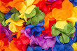 Bright jumble of flower Carnival leis in rainbow colors in a full frame textured background