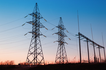 High-voltage power lines at sunset. Electricity distribution station.