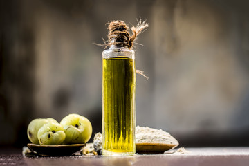 Raw fresh ripe Phyllanthus emblica,amla or Indian gooseberry with its powder and extracted oil on wooden surface.