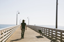 Rear View Of Man Walking On Pier Over Sea Against Clear Sky