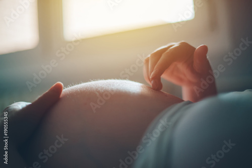 Fotomural Pregnant woman cuddling belly in bedroom at home