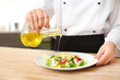 © Africa Studio - Female chef preparing tasty salad in kitchen, closeup