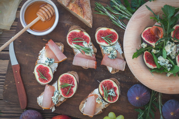 Wall Mural - easy diet salad with arugula, figs and blue cheese on a brown wooden surface. sandwiches with ricott