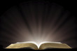 A Book that looks like a Bible Open in a Dark Room with Light Pouring Out of it representing enlightment