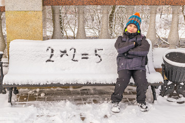 naughty boy wrongly decides an example on a snow-covered bench