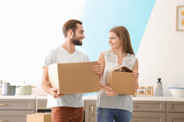 Poster - Young couple with moving boxes in kitchen at new home