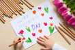 Little boy paints greeting card for Mom on Mother's Day with the inscription 