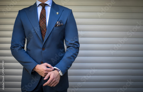 Cuadros en Lienzo Male model in tailored suit posing outdoors and fixing his cufflinks